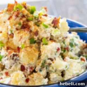 Bacon Potato Salad served in a blue bowl, garnished with green onions.