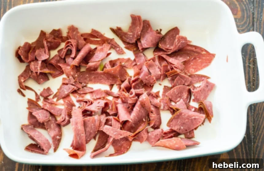 Creamy Company Chicken Bake 3 Roughly chopped chipped beef spread evenly in the bottom of a casserole dish, ready for the next layer of chicken.