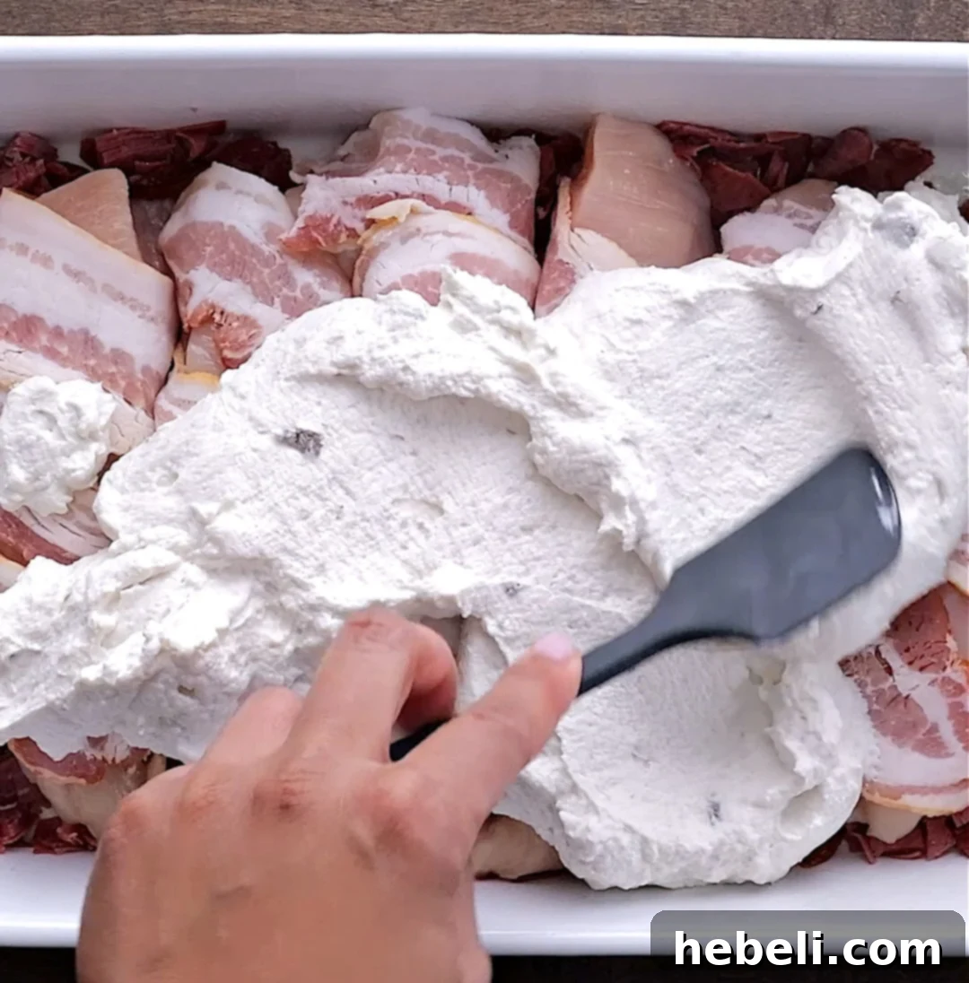 Creamy Company Chicken Bake 5 Creamy mixture of sour cream and condensed cream of mushroom soup spread generously over bacon-wrapped chicken pieces in a baking dish.