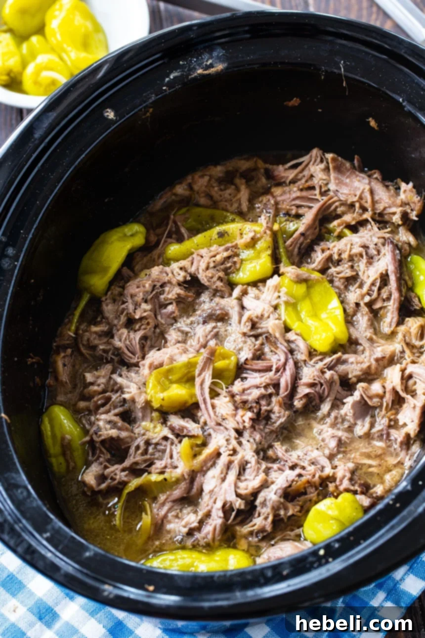 A delicious serving of Slow Cooker Mississippi Pulled Pork, showcasing its rich, shredded texture and a sprinkle of fresh herbs.