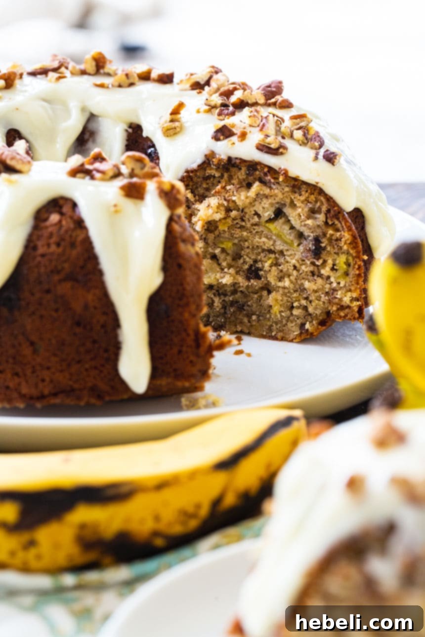 Southern Hummingbird Bundt 5 Hummingbird Bundt Cake served on a rustic wooden board, garnished with additional pecans and a dusting of powdered sugar.