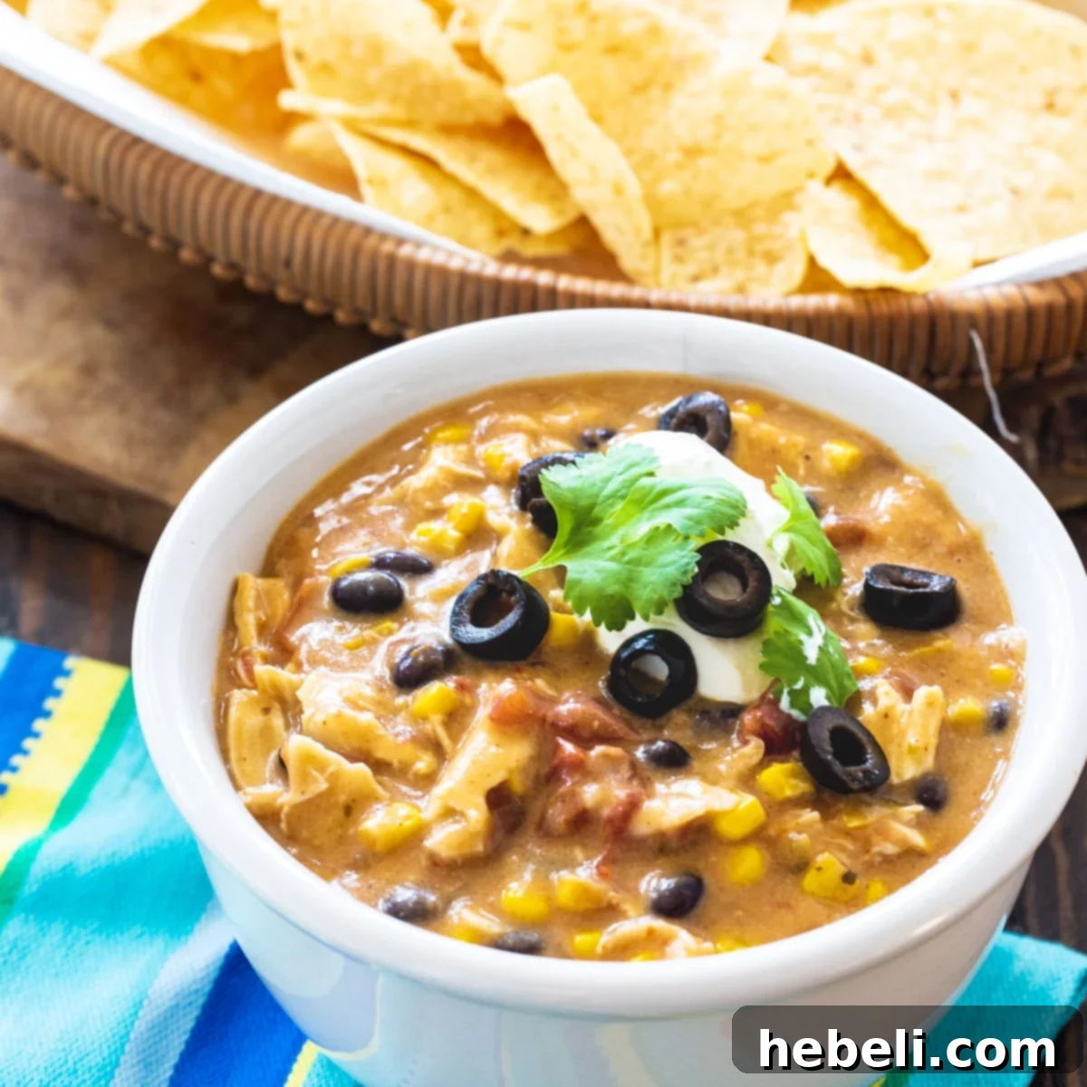 A steaming bowl of Slow Cooker Chicken Tortilla Soup garnished with fresh cilantro and cheese.