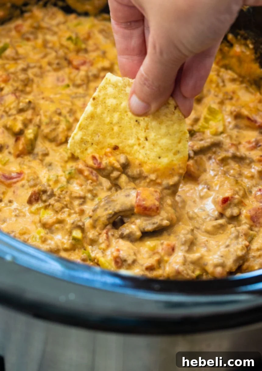 Tortilla chip generously loaded with creamy Crockpot Bacon Cheeseburger Dip, showcasing its rich texture and ready to be enjoyed.
