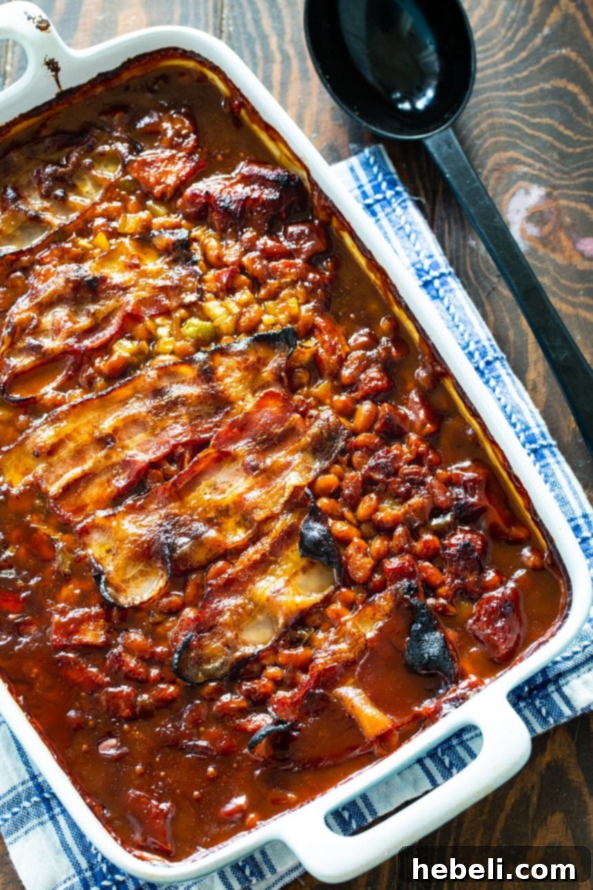 Molasses Baked Beans served in a baking dish with a large serving spoon, ready to be enjoyed at a family gathering or BBQ.