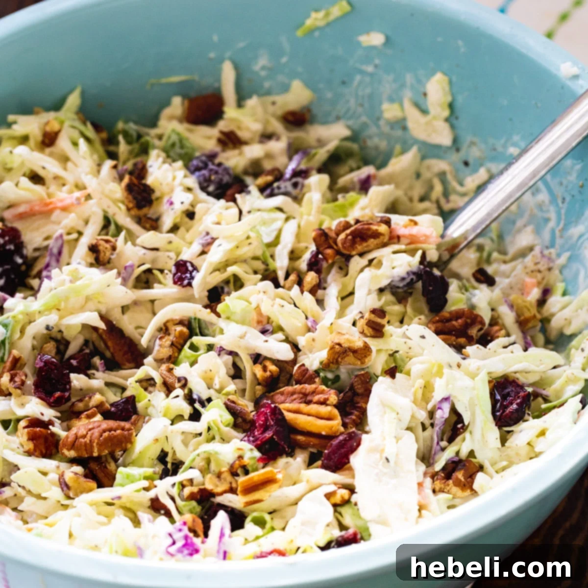 A large blue bowl filled with vibrant Cranberry Pecan Coleslaw, showcasing the creamy dressing, crunchy cabbage, red cranberries, and toasted pecans.