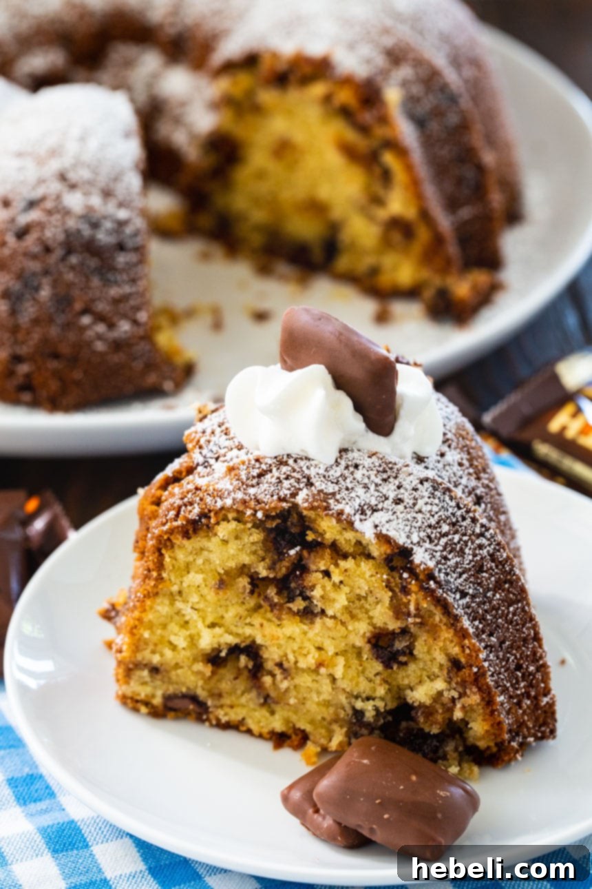 A close-up shot of the Toffee Bundt Cake, showcasing the golden-brown crust and the visible milk chocolate chips along with crushed Heath bars embedded in the cake.