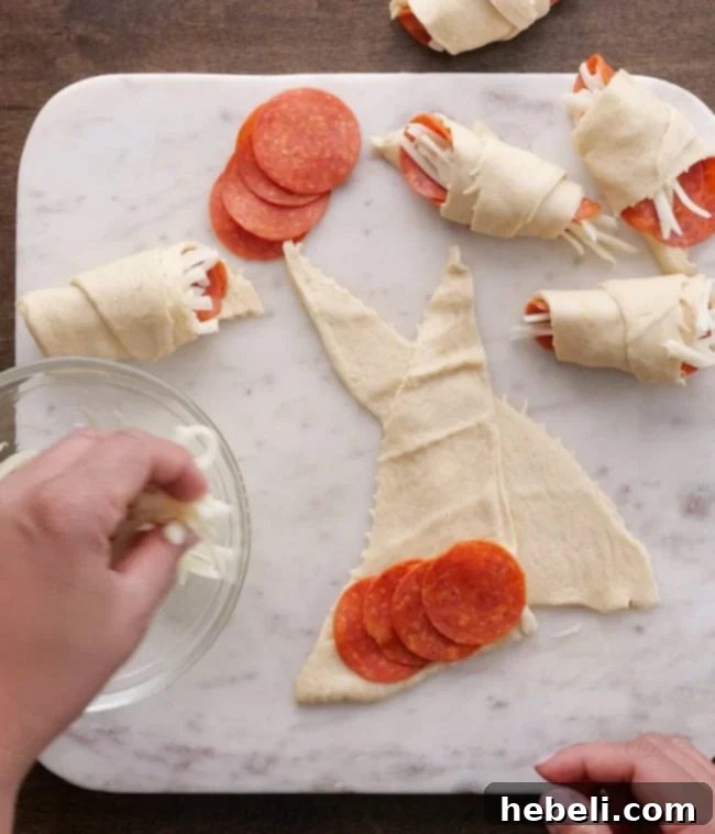 Carefully placing pepperoni slices and shredded mozzarella cheese onto an unrolled crescent dough triangle on a baking sheet.