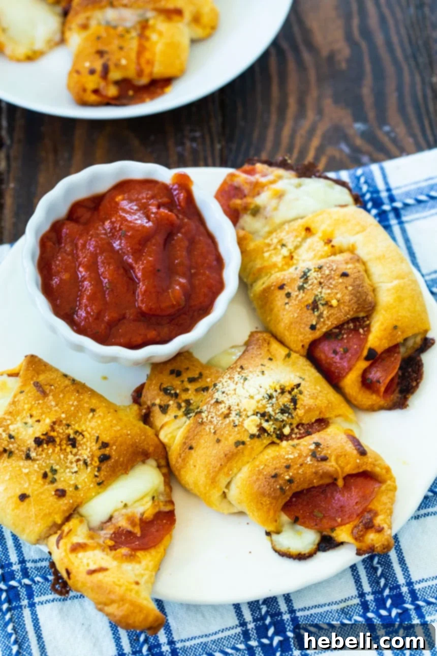 Three perfectly baked, golden Pepperoni Crescent Rolls resting on a pristine white plate, showcasing their inviting texture.