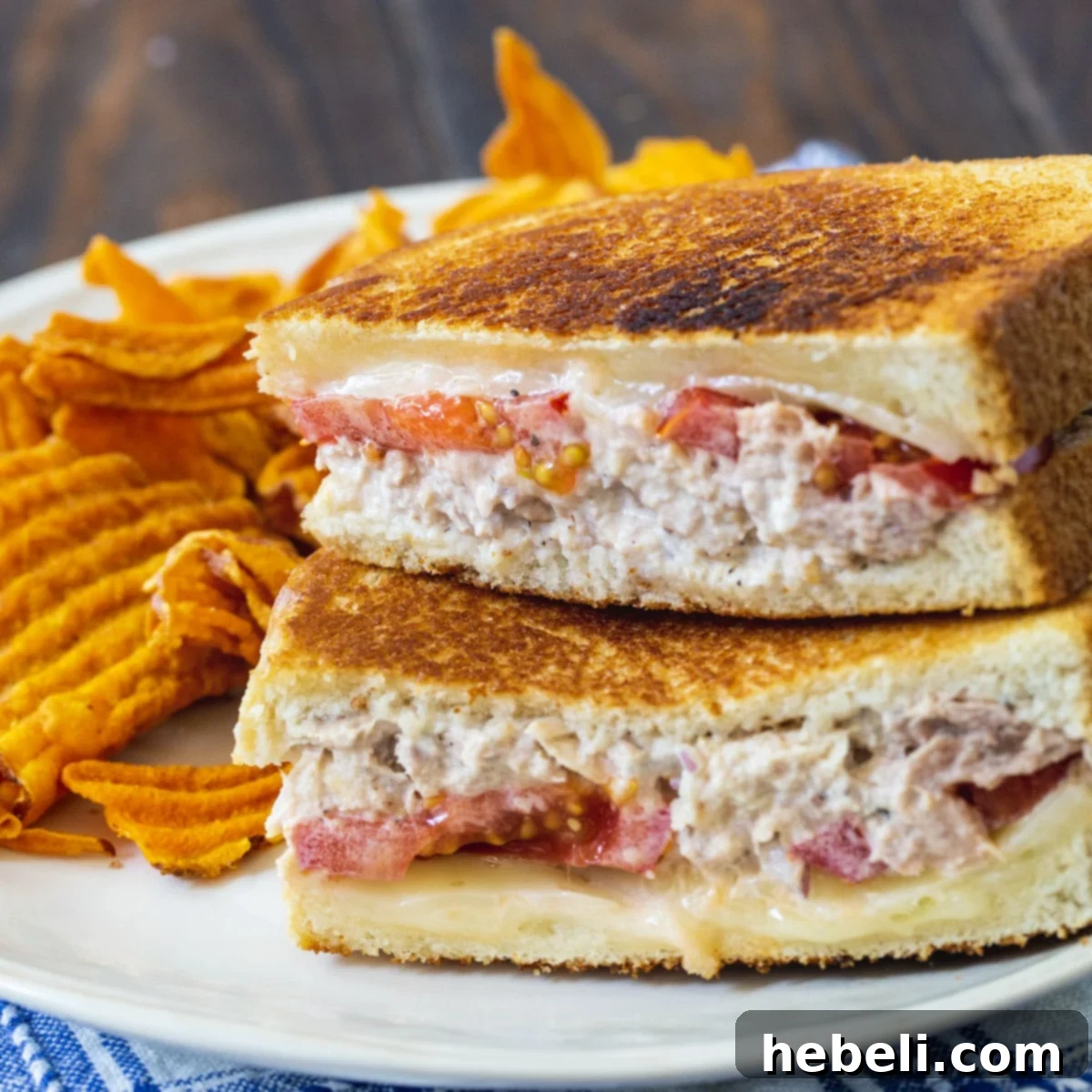 Golden Tuna Melt 2 A perfectly made Classic Tuna Melt sandwich, golden brown and oozing with melted Swiss cheese, served on a plate.