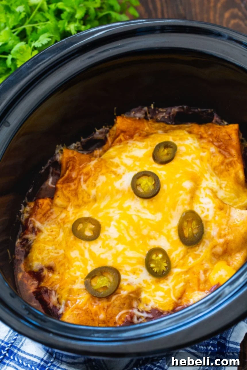 3-Ingredient Smothered Burritos cooking in a slow cooker, covered in rich red sauce.