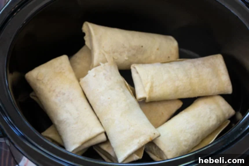 Frozen burritos arranged neatly in a 6-quart slow cooker before adding sauce.