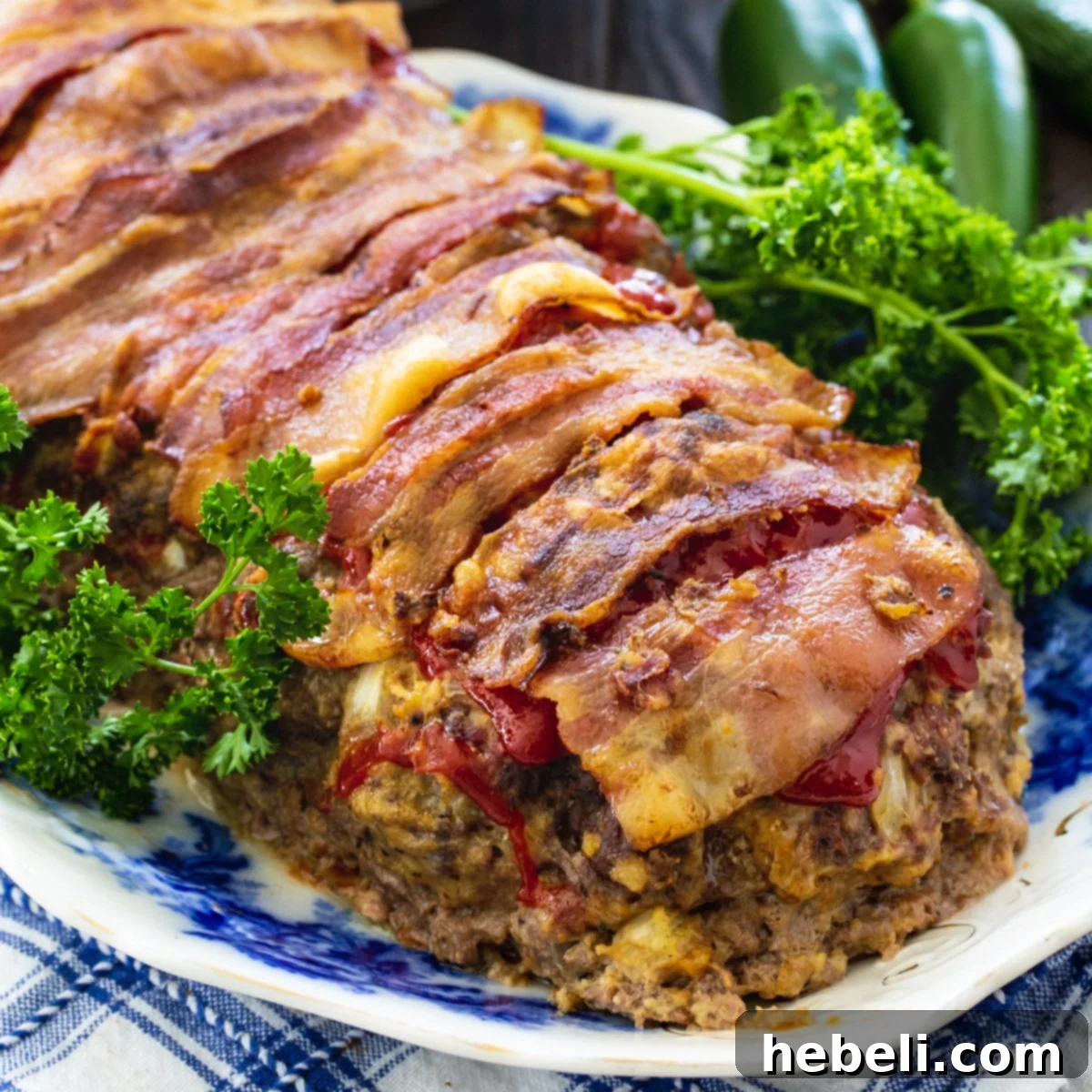 Jalapeño Popper Meatloaf Extravaganza 2 Jalapeno Popper Stuffed Meatloaf on serving platter with parsley, showcasing the bacon wrap.