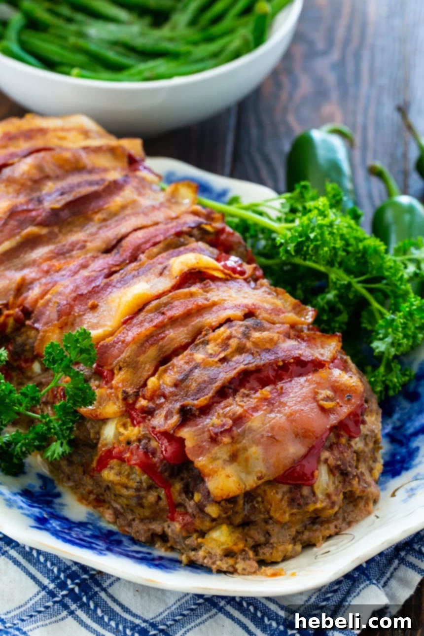Jalapeño Popper Meatloaf Extravaganza 3 Jalapeno Popper Meatloaf on a plate with fresh parsley and green beans in the background, ready to be served.
