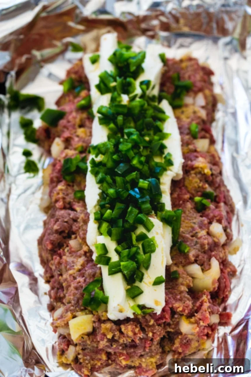 Jalapeño Popper Meatloaf Extravaganza 4 Meatloaf mixture with cream cheese and diced jalapenos layered on top, ready to be shaped.