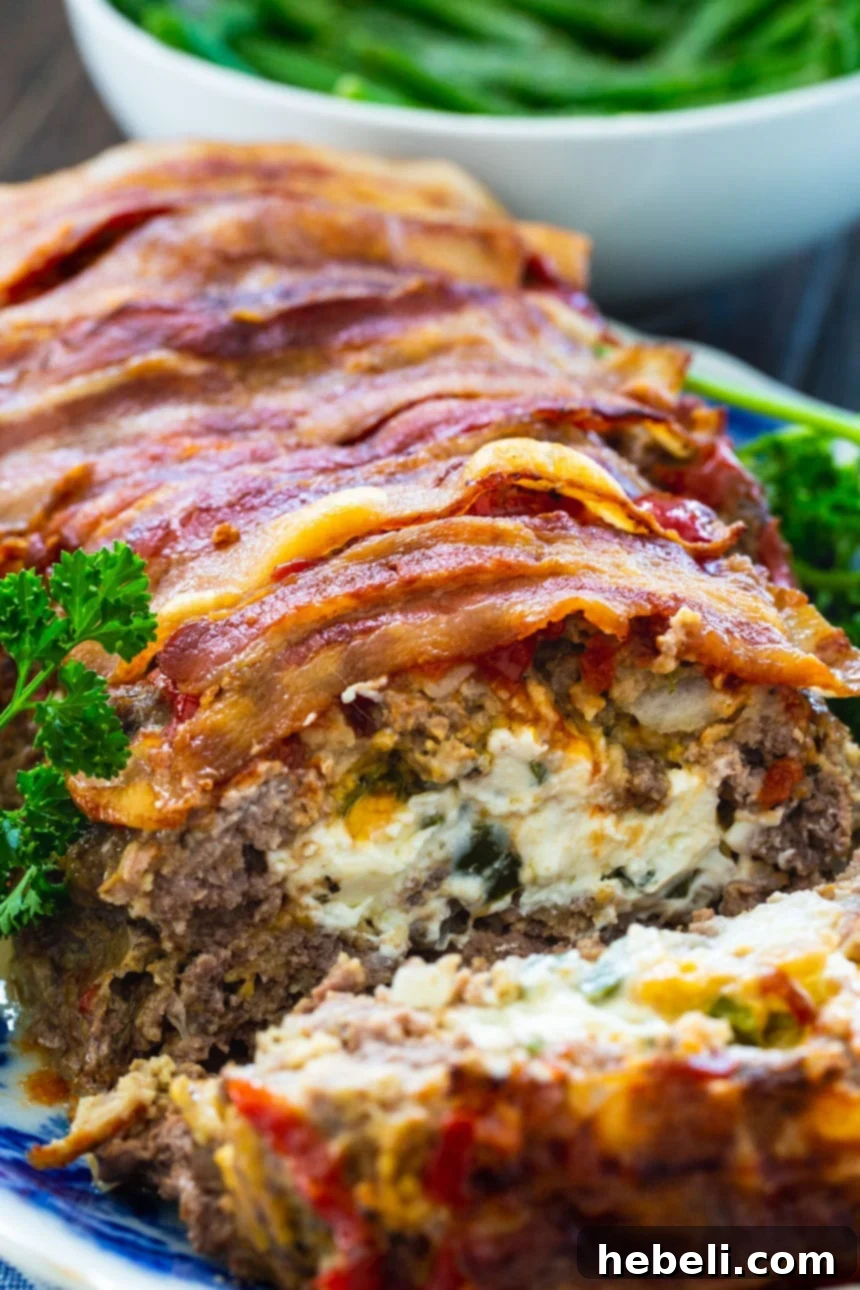 Jalapeño Popper Meatloaf Extravaganza 5 A freshly baked Jalapeno Popper Stuffed Meatloaf with a slice cut to show the creamy, jalapeno-filled interior and crispy bacon.