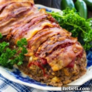 Meatloaf wrapped in bacon on a serving platter with parsley