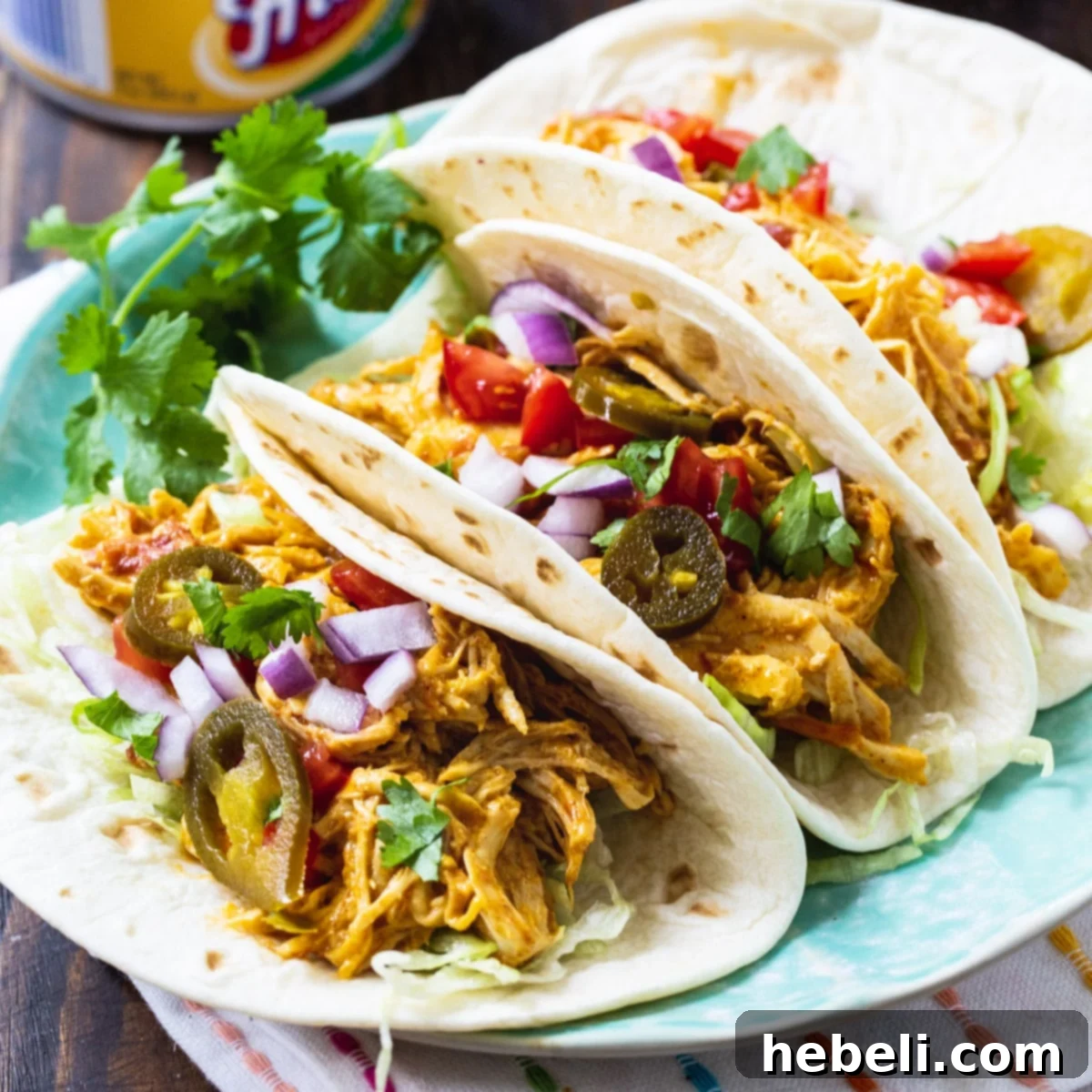 Cheesy Fiesta Crock-Pot Chicken 2 Slow Cooker Nacho Chicken in soft shell tacos, garnished with cilantro.