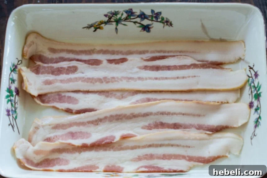 Savory Bacon Chicken Rice Bake 3 Close-up of a baking dish with crispy bacon strips arranged in a single layer at the bottom, ready for the chicken and rice mixture.