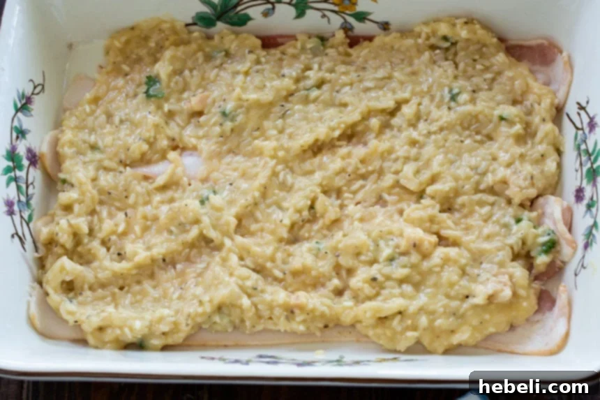 Savory Bacon Chicken Rice Bake 4 A creamy mixture of rice and chicken soup being spread evenly over a layer of bacon in a casserole dish.