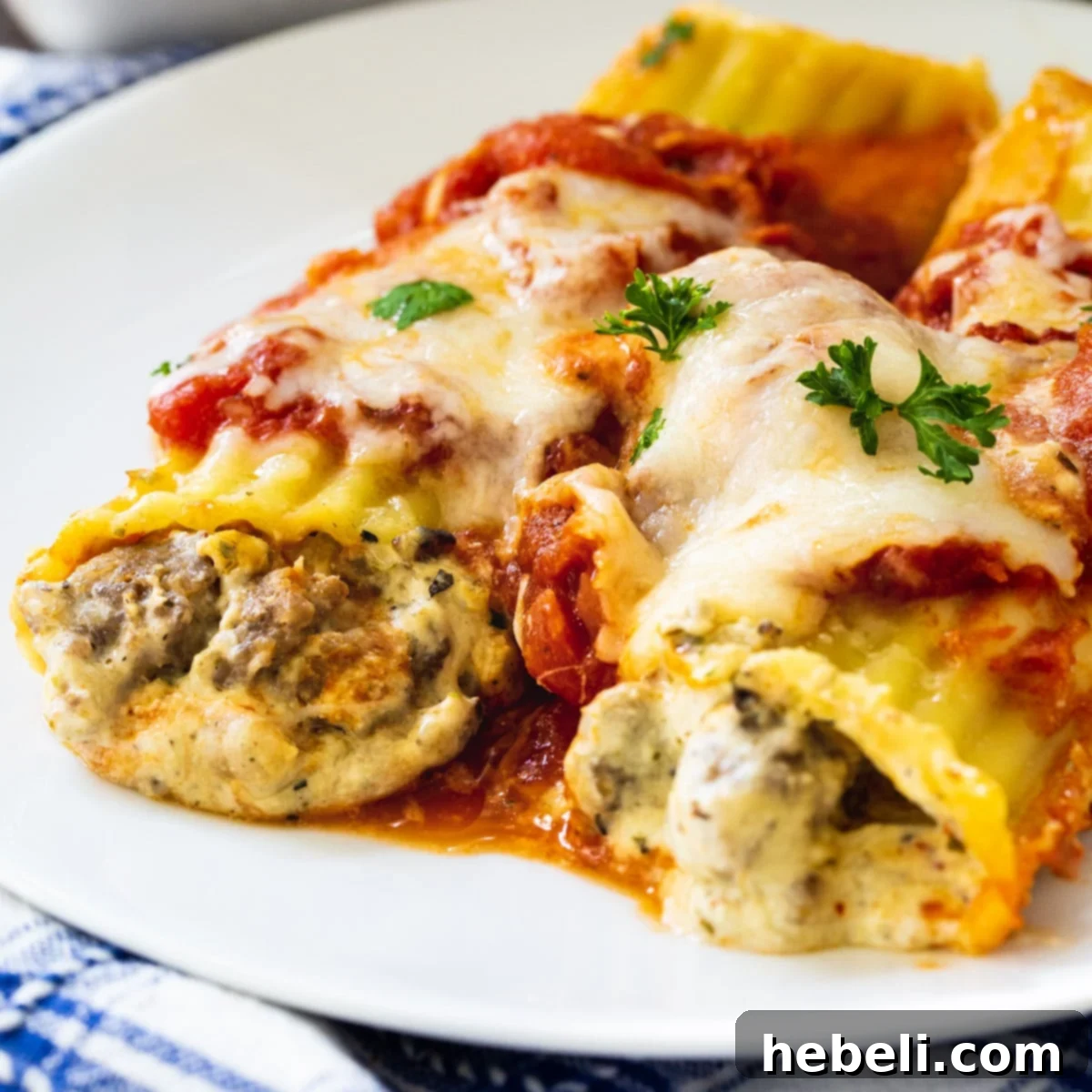 Two Italian Sausage Manicotti on a plate, garnished with fresh parsley.