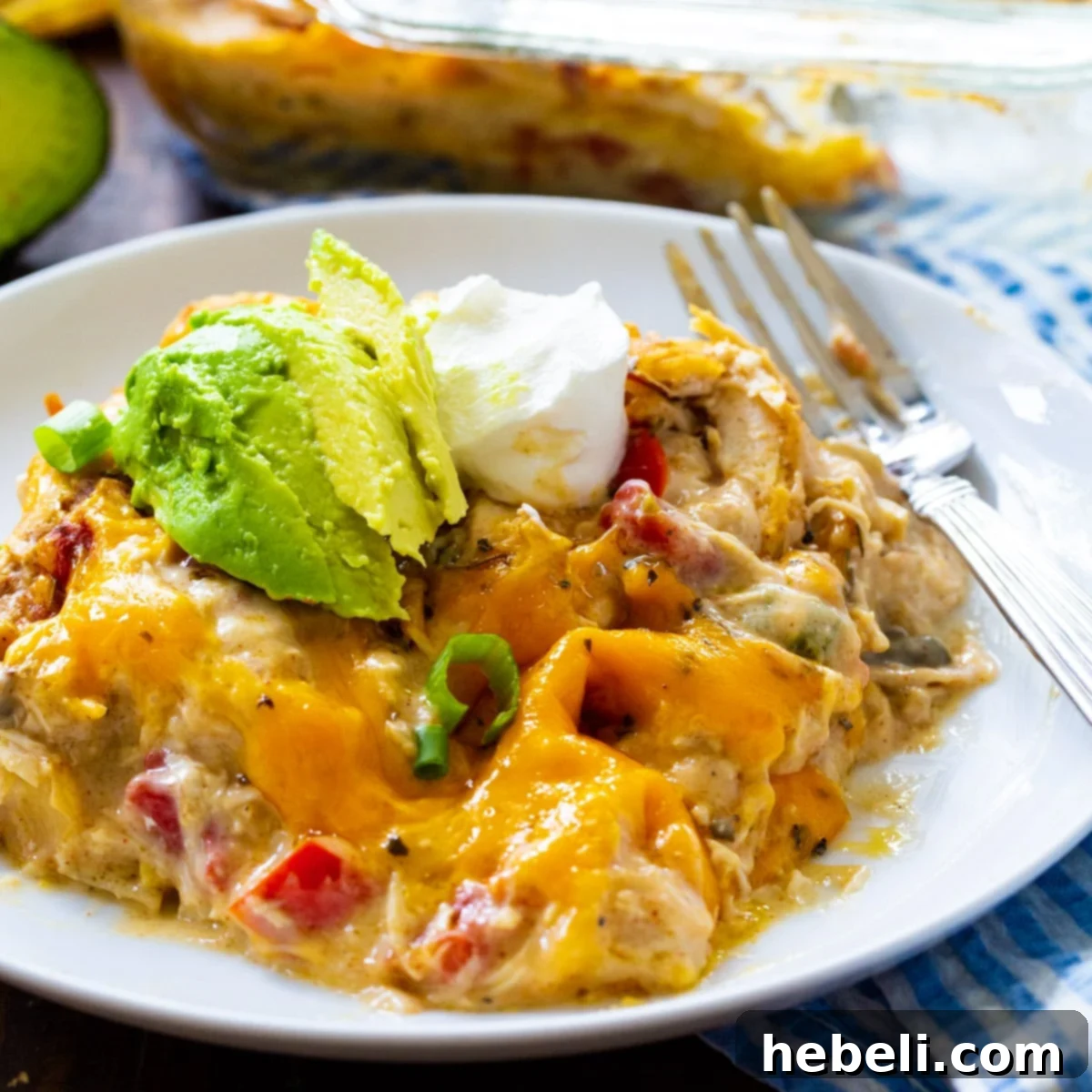 Hearty King Ranch Chicken Casserole 2 King Ranch Chicken Casserole topped with fresh avocado slices on a white plate, showcasing its vibrant colors and creamy texture.