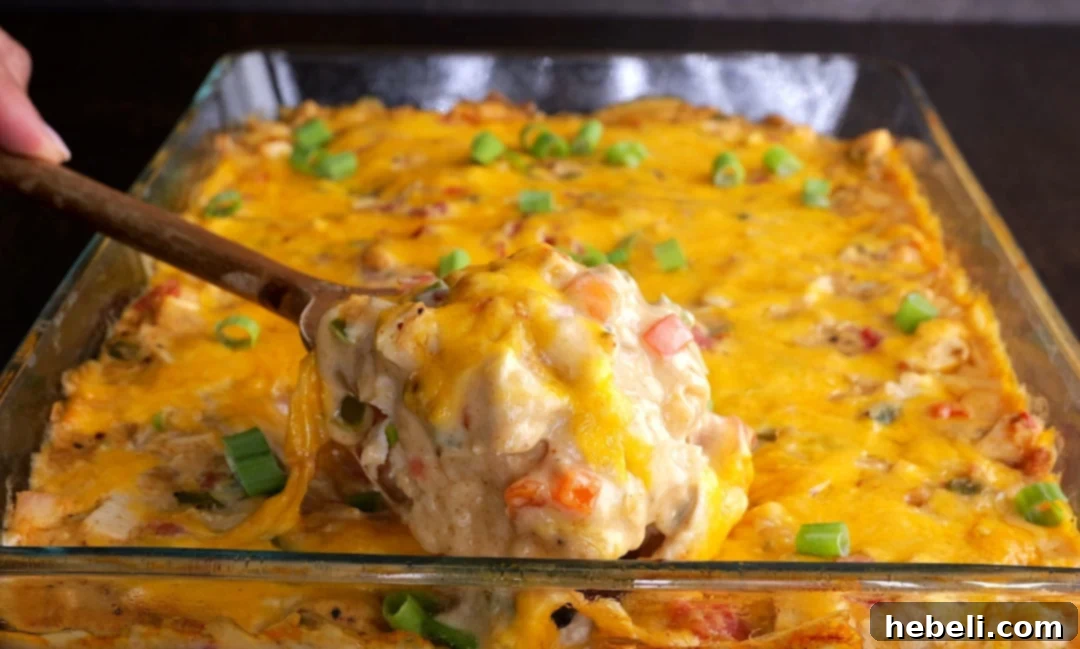 Hearty King Ranch Chicken Casserole 10 A serving spoon lifting a portion of King Ranch Chicken Casserole from a baking dish, revealing the rich layers.