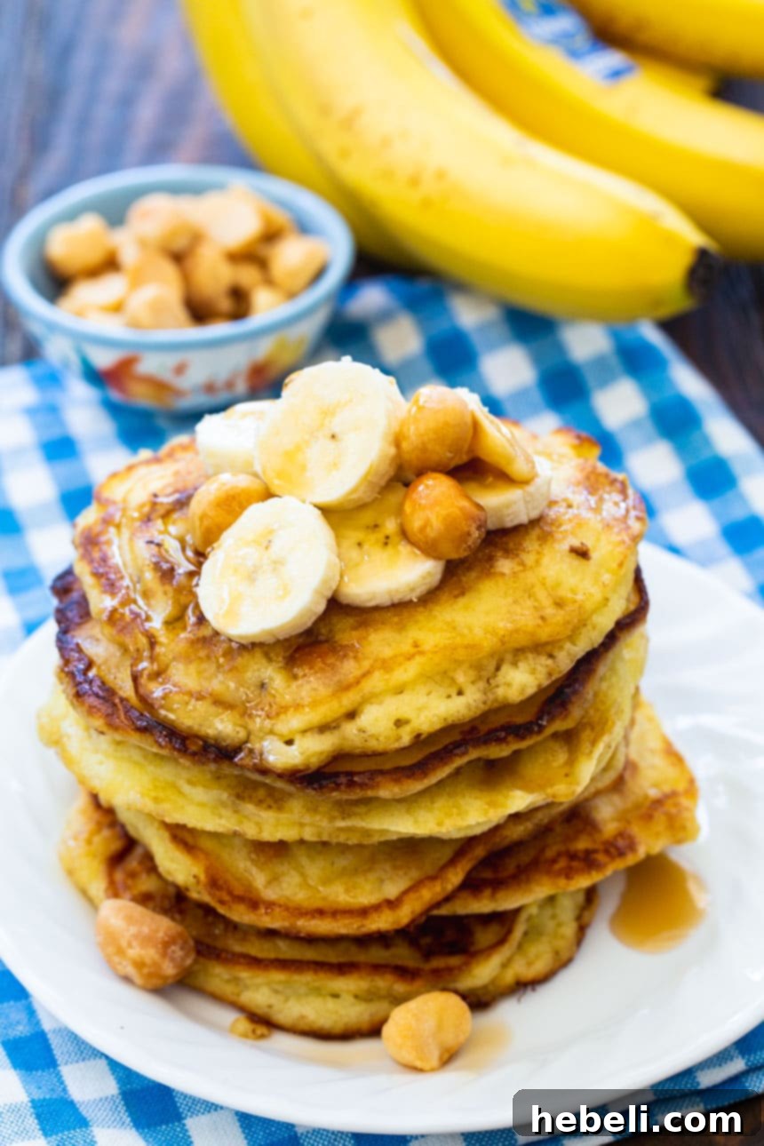 Plate of Banana Macadamia Nut Pancakes with fresh banana slices and a whole macadamia nuts in the background.