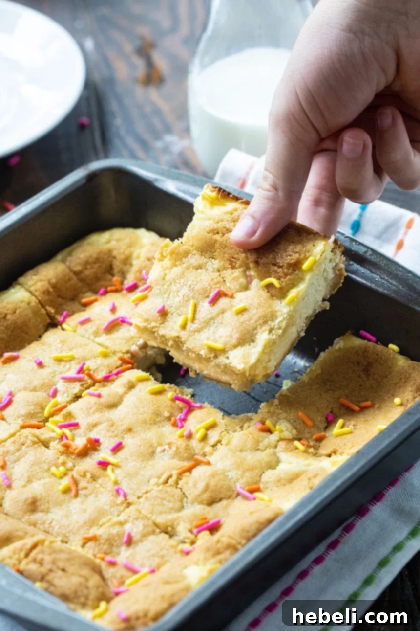 Cheesecake Bars made from Sugar Cookie dough in an 8-inch baking dish, showing the layers before baking.