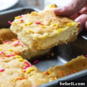 Hand picking up a Sugar Cookie Cheesecake Bars