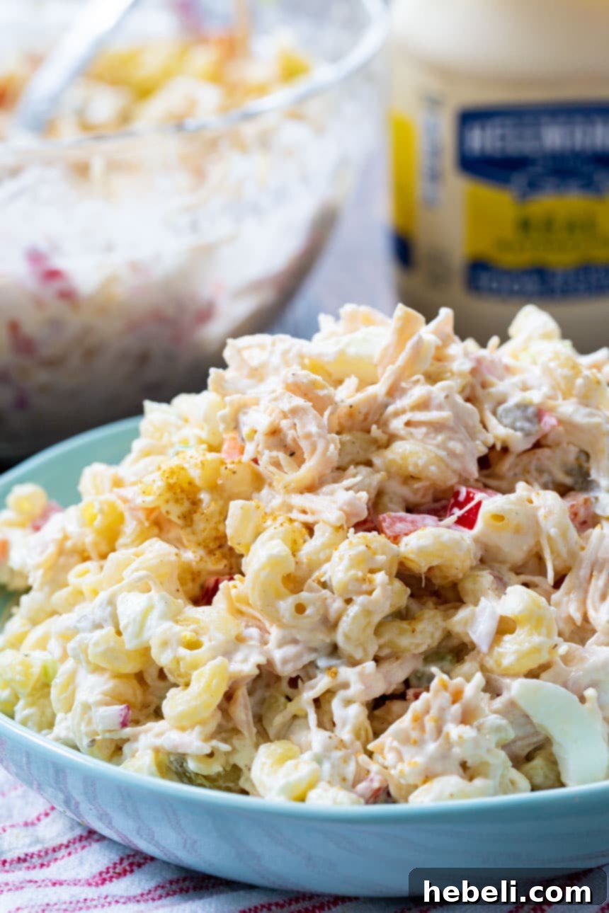 Creamy Chicken Pasta Salad 4 Chicken Macaroni Salad in a blue serving bowl with a jar of mayonnaise in the soft-focus background.
