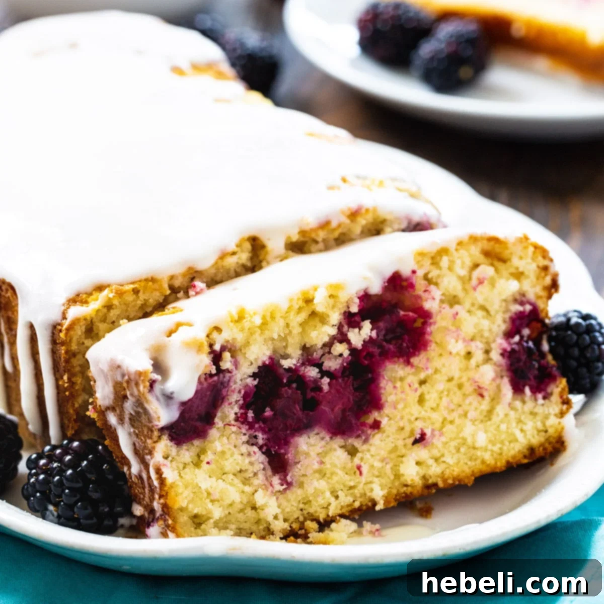 A perfectly baked Blackberry Buttermilk Loaf Cake with a slice cut, revealing the sweet, juicy blackberries embedded within its tender crumb.