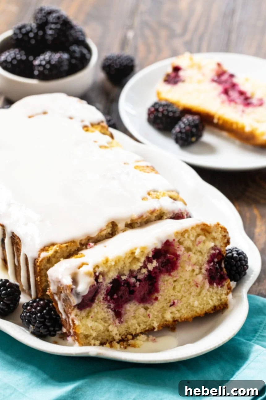 A close-up view of the Blackberry Buttermilk Loaf Cake, adorned with fresh blackberries, highlighting the vibrant fruit and texture.