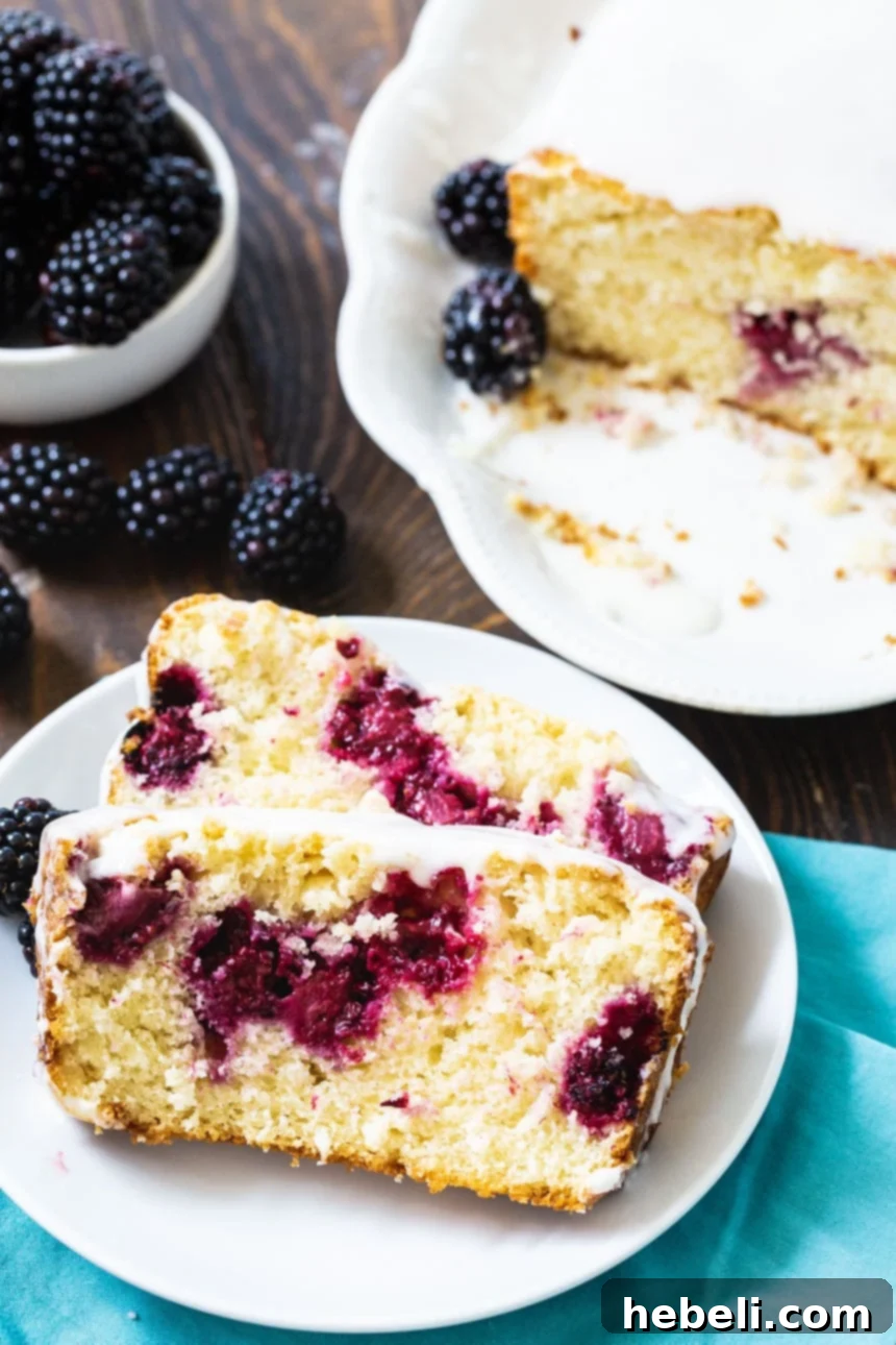 Two perfectly glazed slices of Blackberry Buttermilk Loaf Cake displayed on a white plate, invitingly ready to be enjoyed.