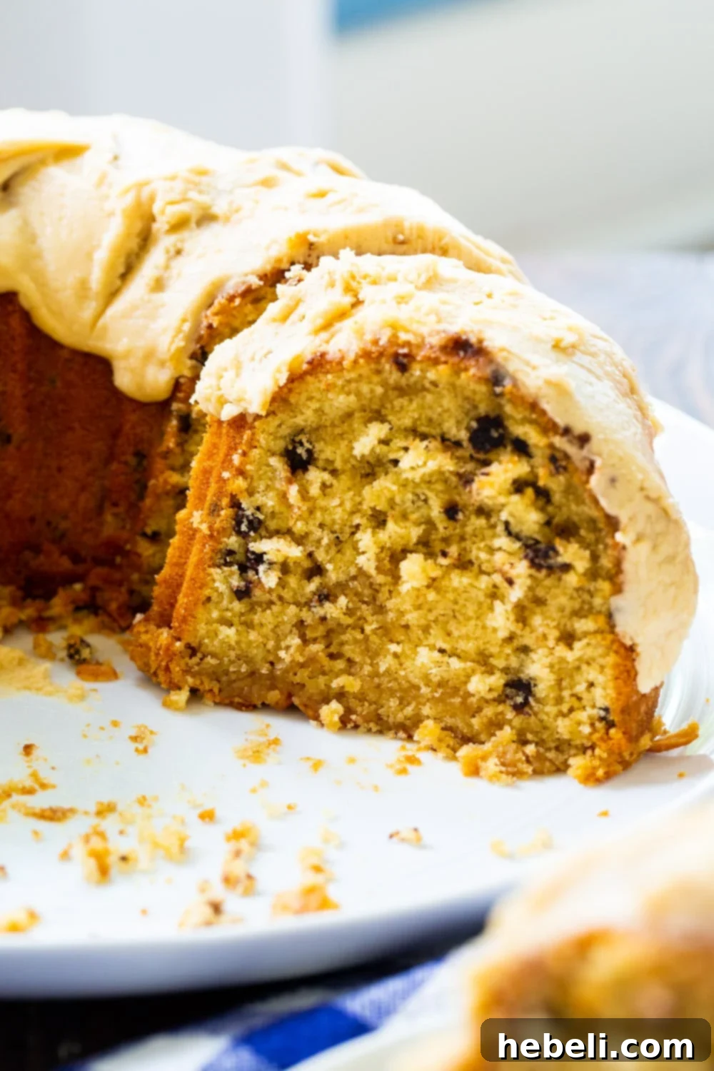 Decadent Peanut Butter Bundt 3 A beautifully baked Peanut Butter Bundt Cake, half-cut and presented on a decorative serving platter, drizzled with creamy peanut butter icing.