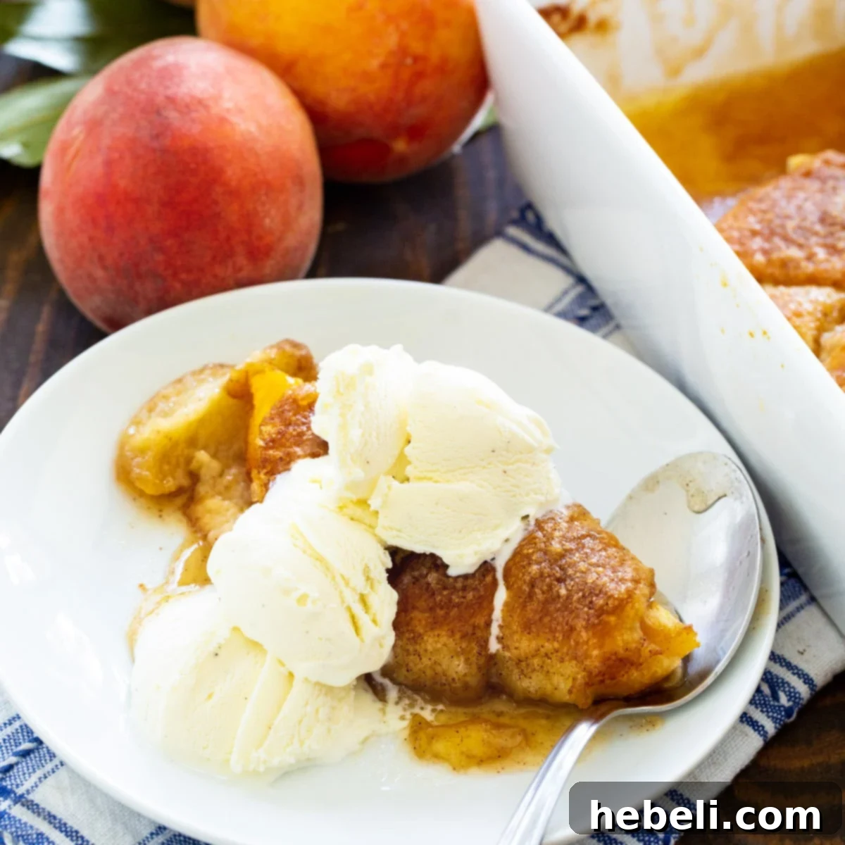 A golden-baked Peach Crescent Dumpling on a plate, served alongside a scoop of melting vanilla ice cream, hinting at its warm, delicious interior.