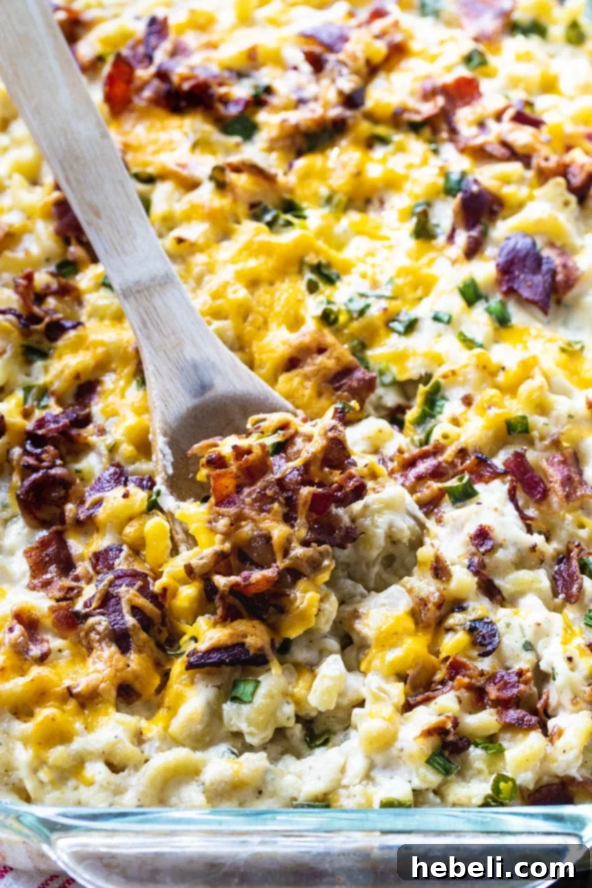 Loaded Chicken Bacon and Ranch Mac and Cheese 4 Close-up of a wooden spoon scooping creamy Chicken, Bacon & Ranch Mac & Cheese from a bowl, emphasizing the rich sauce and perfectly cooked ingredients.