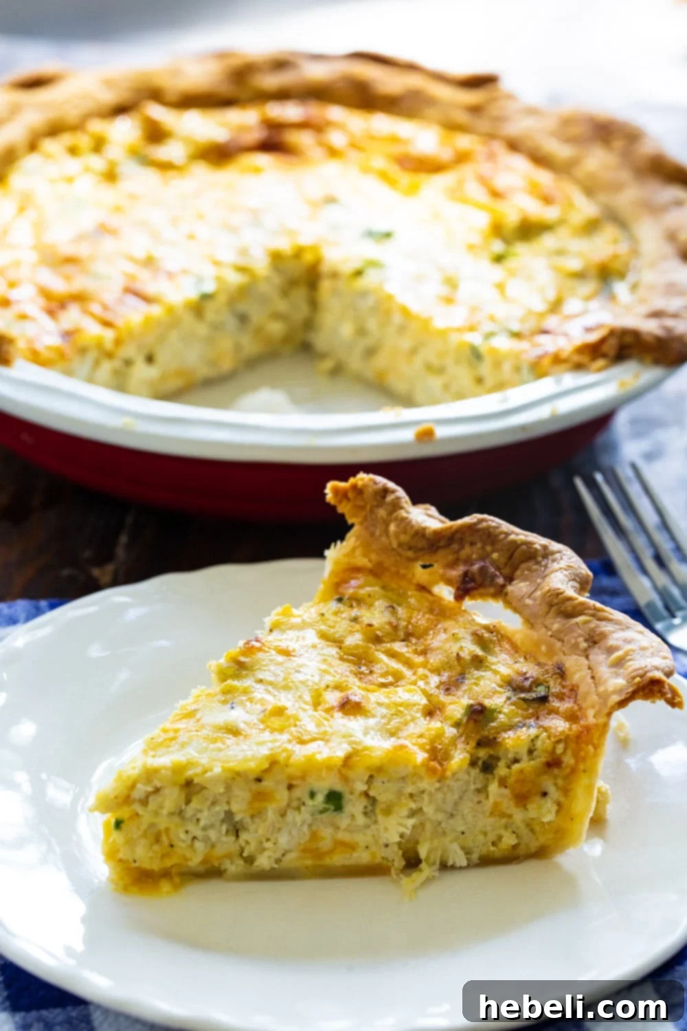 Savory Crab Pie 3 A slice of golden-brown Crab Pie, with the remaining pie in the background, ready to be enjoyed.