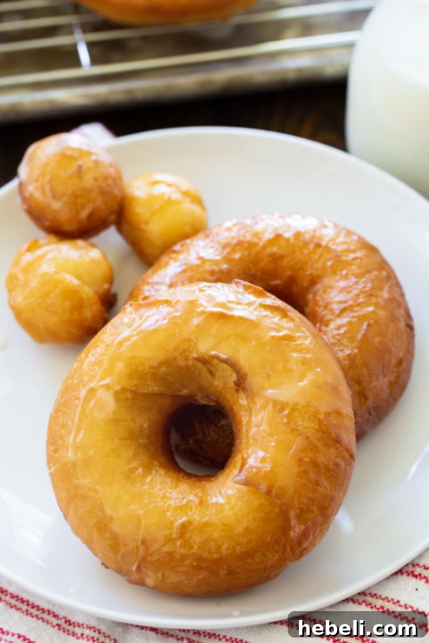 Homemade Krispy Kreme Style Doughnuts 3 A plate filled with freshly fried, unglazed doughnuts and their centers, known as doughnut holes, awaiting their sweet glaze.