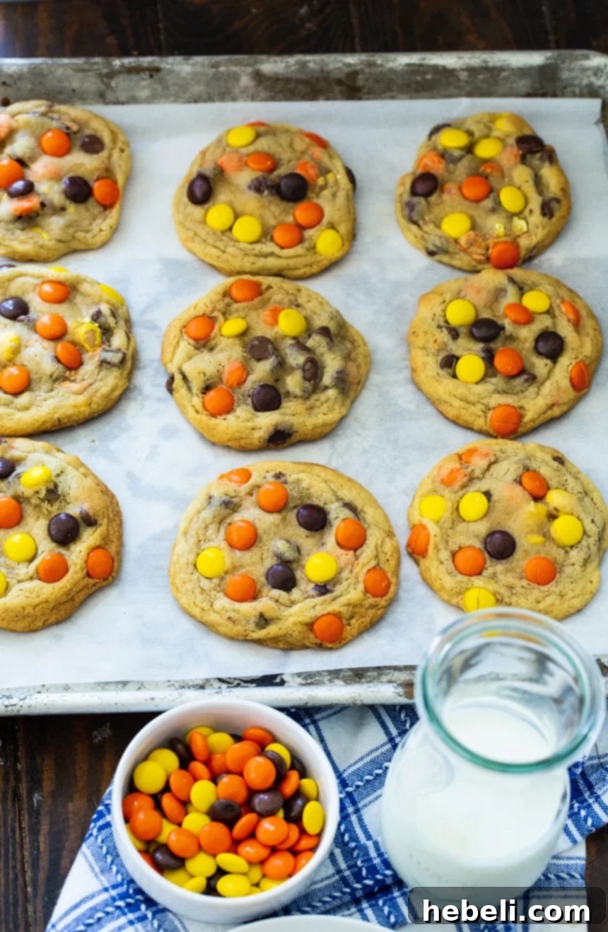 Soft Baked Reeses Pieces Cookies 3 Freshly baked Reese's Pieces cookies cooling on a parchment-lined baking sheet.