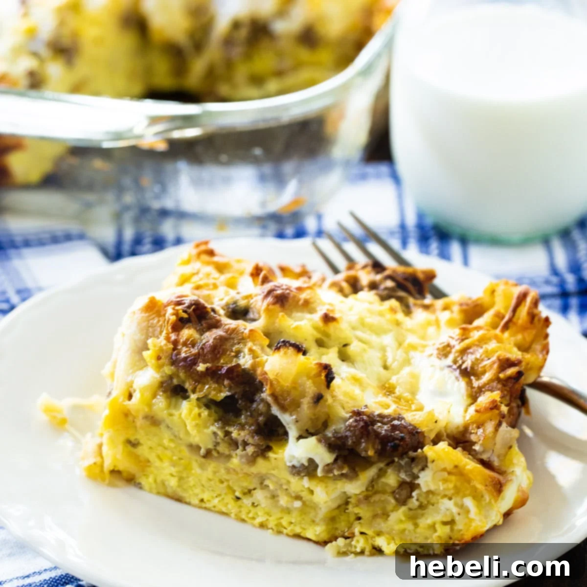 A delectable slice of Sausage and Cheese English Muffin Breakfast Casserole, showcasing layers of sausage, cheese, eggs, and English muffins, served on a white plate, ready to be enjoyed.