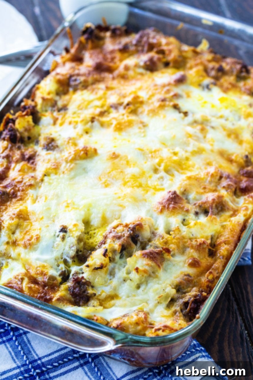 The full English Muffin Breakfast Casserole sits baking in a standard 9x13-inch baking dish, bubbling with cheese and ready to be served, highlighting its suitability as a great make-ahead breakfast option.