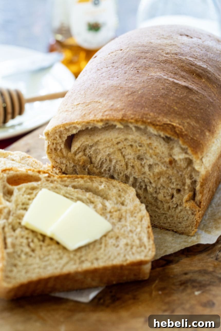 Slice of bread topped with butter next to the rest of the loaf on a cutting board.