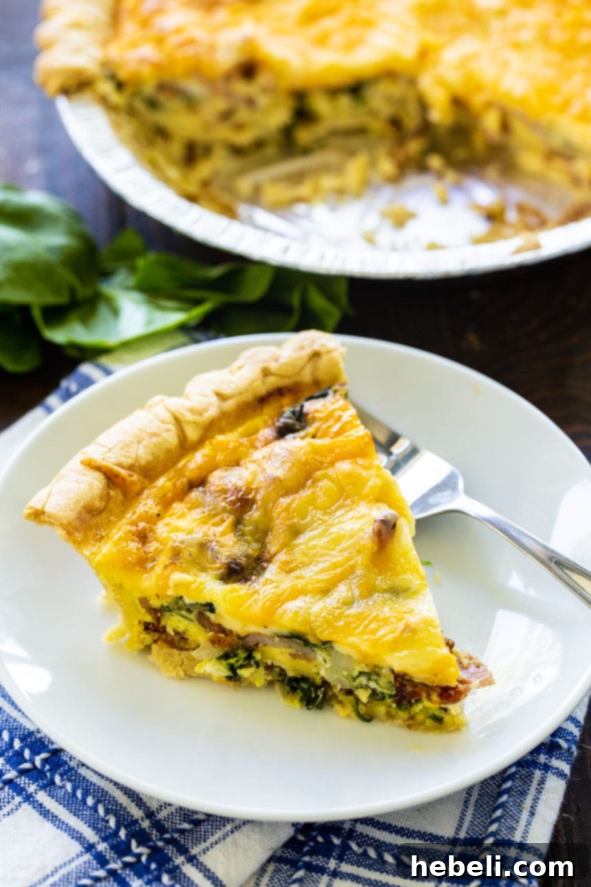 A golden-brown slice of Bacon Florentine Quiche on a plate, with the full quiche in the background.