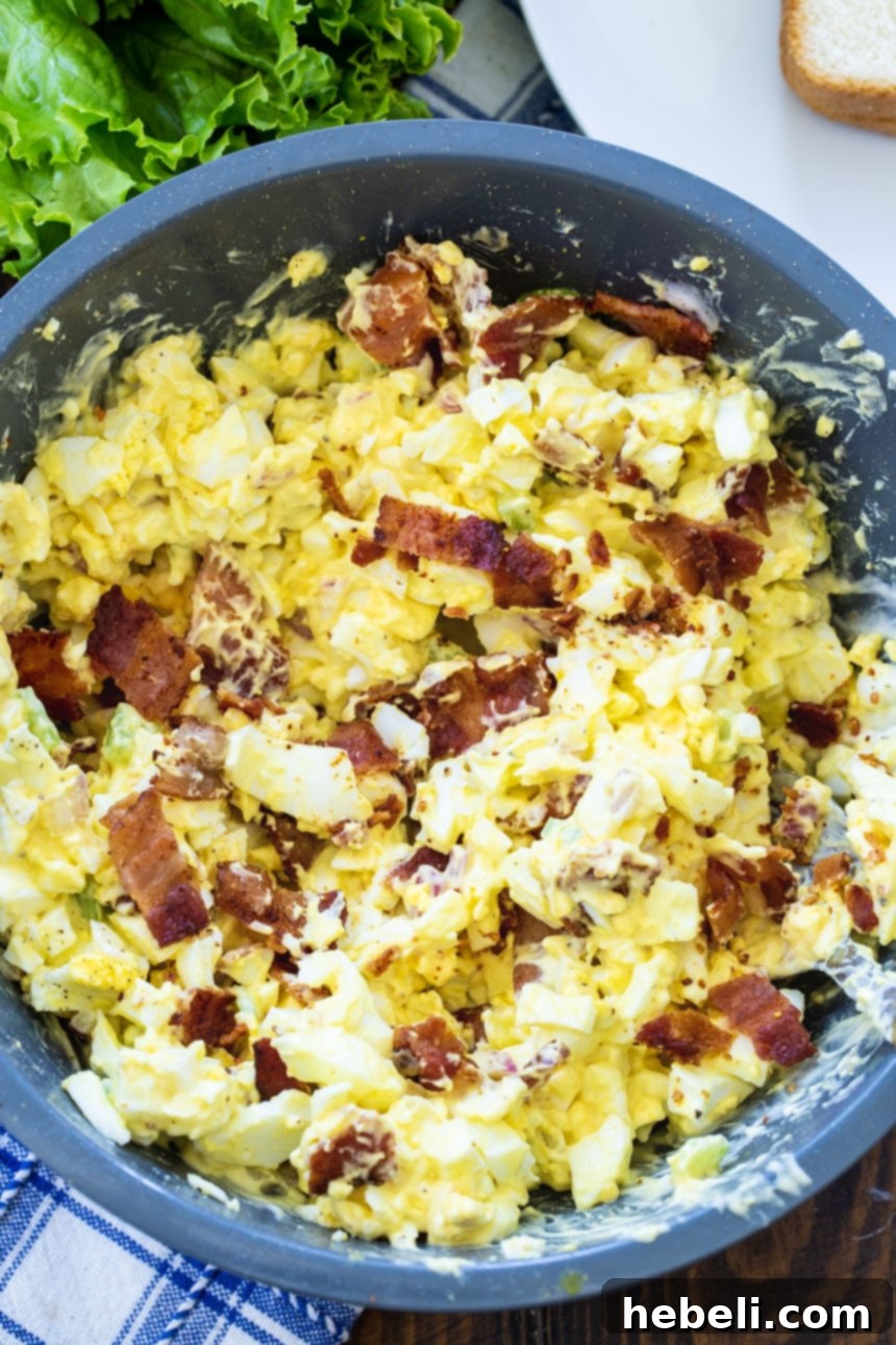 Creamy Bacon Egg Salad served in a large blue serving bowl, garnished and ready to be shared.