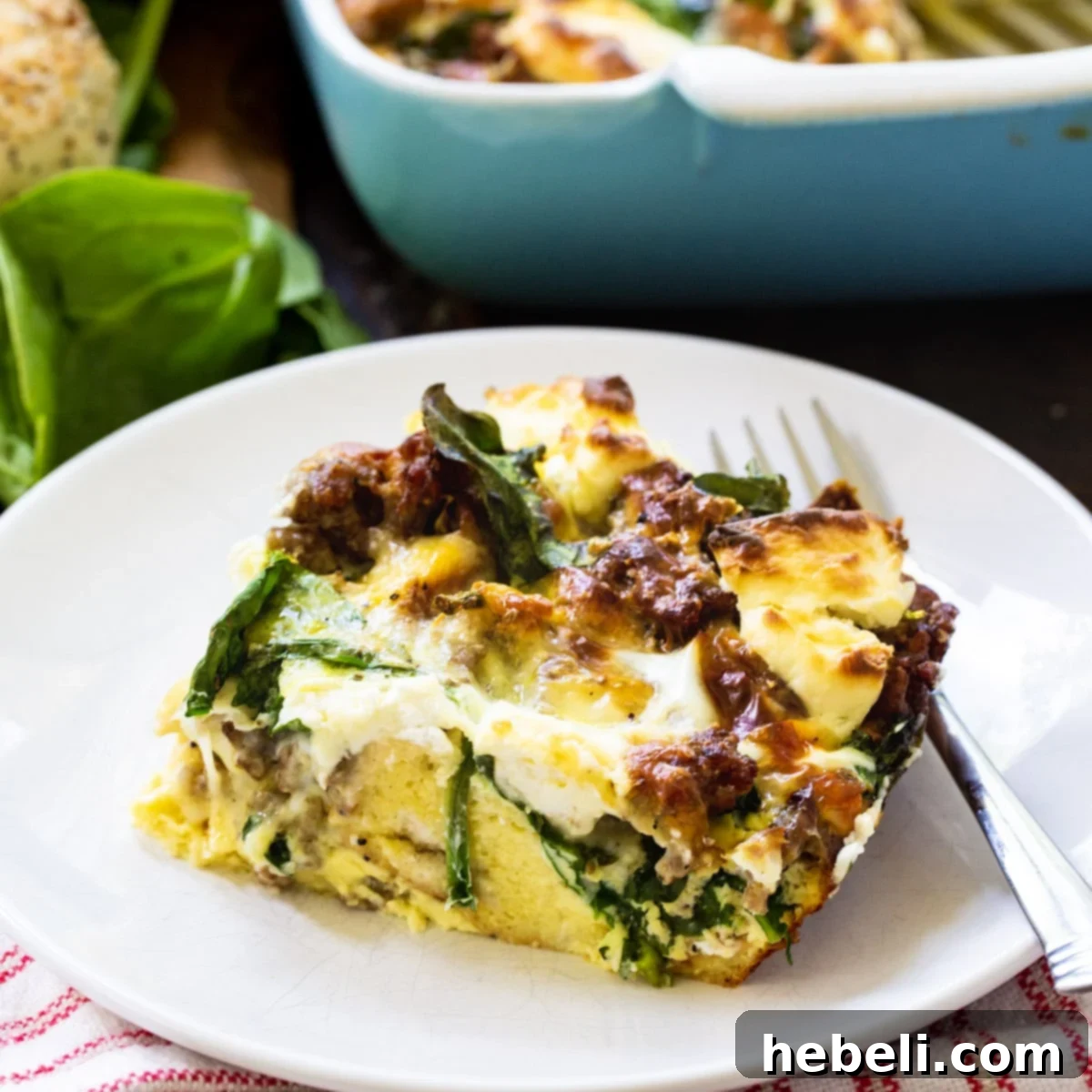 A perfectly portioned slice of Everything Bagel Breakfast Casserole resting on a plate, showcasing its golden-brown top, melted cheese, savory sausage, and bagel pieces.