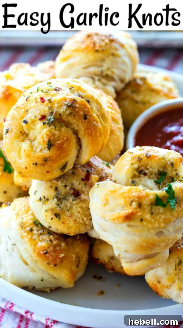 A large pile of freshly baked, golden, buttery garlic knots on a plate, ready to be enjoyed.
