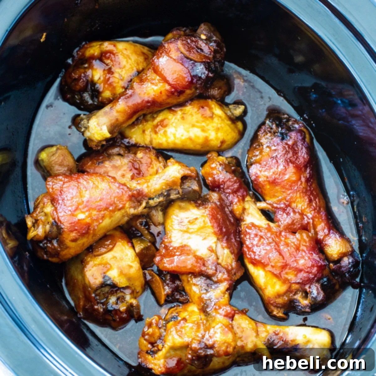 Garlic Peach Chicken Legs simmering in a slow cooker, featuring a vibrant, sweet and spicy glaze.