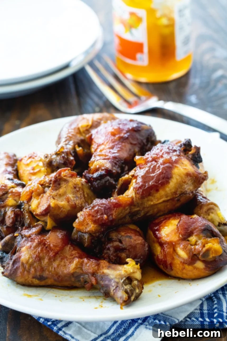 Two Garlic Peach Chicken Legs on a white plate, garnished with fresh herbs, showcasing the rich, caramelized glaze.