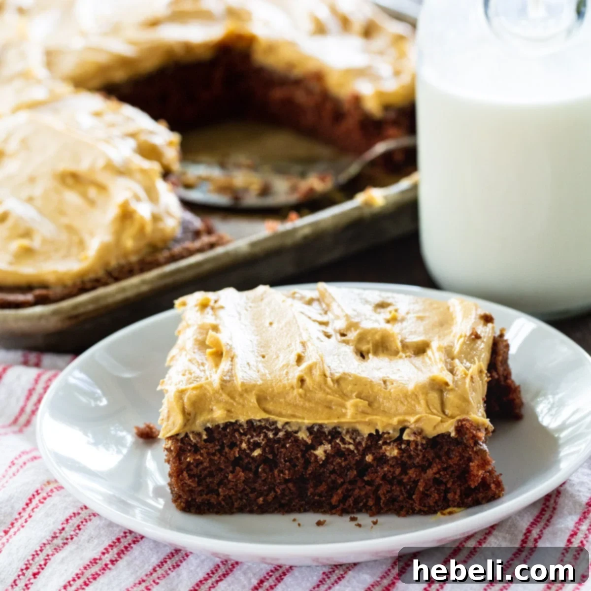 Creamy Peanut Butter Texas Sheet Cake 2 A delectable slice of Texas Sheet Cake with Peanut Butter Frosting artfully placed on a plate, with the full, frosted cake visible in the background, inviting guests to enjoy.