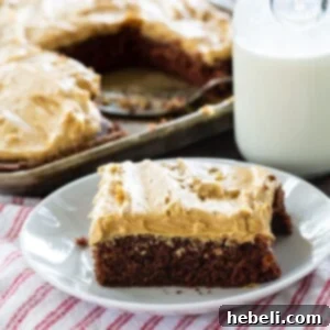 Creamy Peanut Butter Texas Sheet Cake 5 A beautifully presented slice of Texas Sheet Cake with peanut butter frosting on a small white plate, accompanied by a jug of milk, ready for a delightful indulgence.